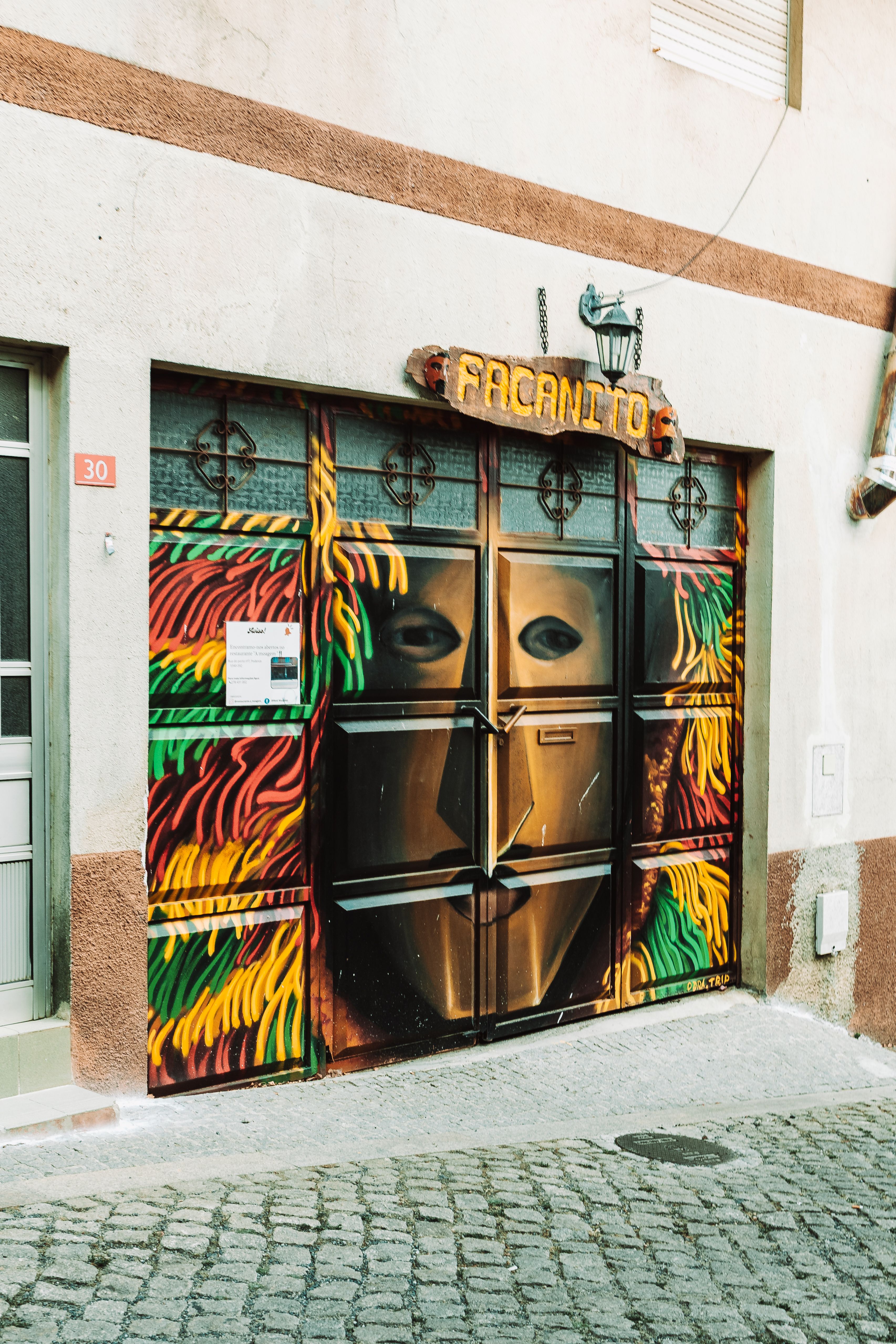 Colorful street art mural featuring a masked figure in Macedo de Cavaleiros, Portugal.