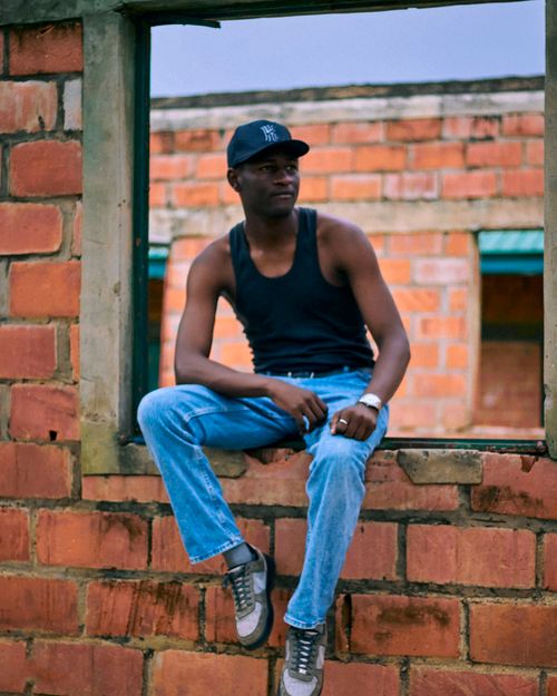 Free Casual pose of a man sitting in an open window frame in a brick building. Stock Photo