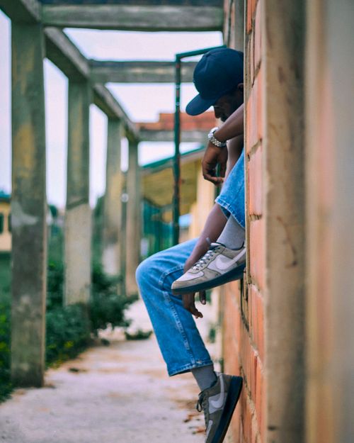 Free A young adult in casual attire sitting on an urban wall, conveying a relaxed vibe. Stock Photo