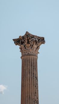 Close-up view of a Corinthian column in Pompeii, Italy, showcasing intricate carvings against a clear sky.