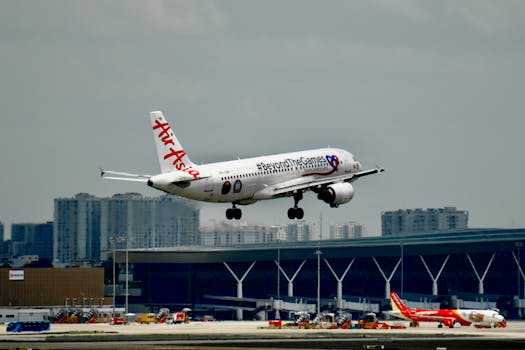 AirAsia plane landing at urban airport with city skyline in background.