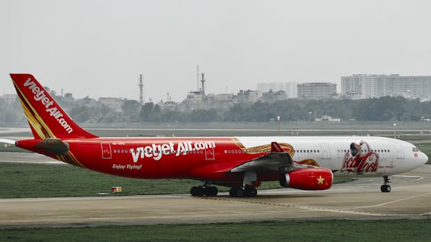 A VietJet airplane on the runway near an urban skyline. Ideal for travel imagery.