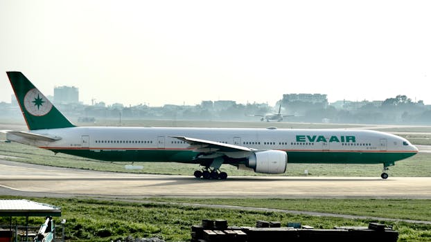 EVA Air plane on runway during sunrise, with a cityscape in the background.
