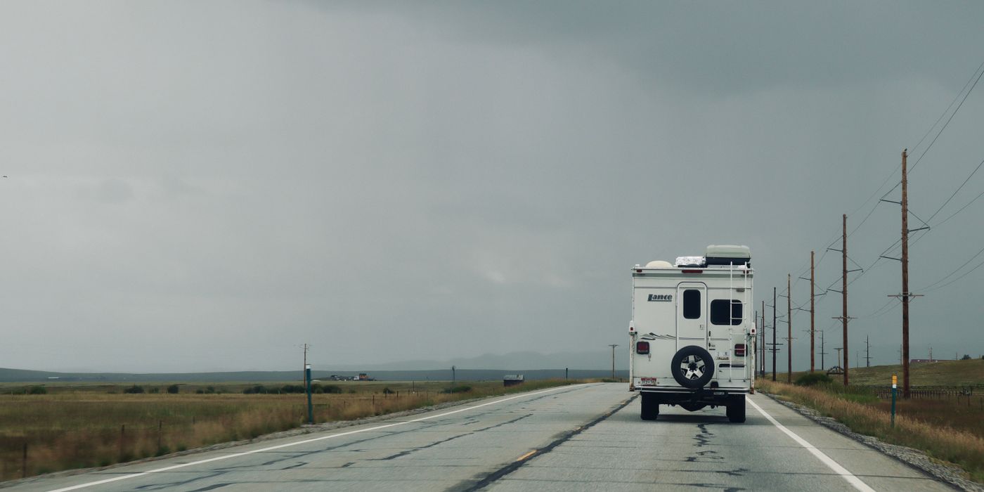 A motorhome on an empty highway under dark rain clouds