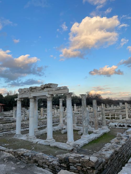 Free Explore ancient ruins with classic columns set against a vibrant blue sky and scattered clouds. Stock Photo