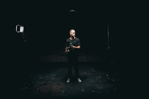 Man Standing in the Middle of a Dark Room ]