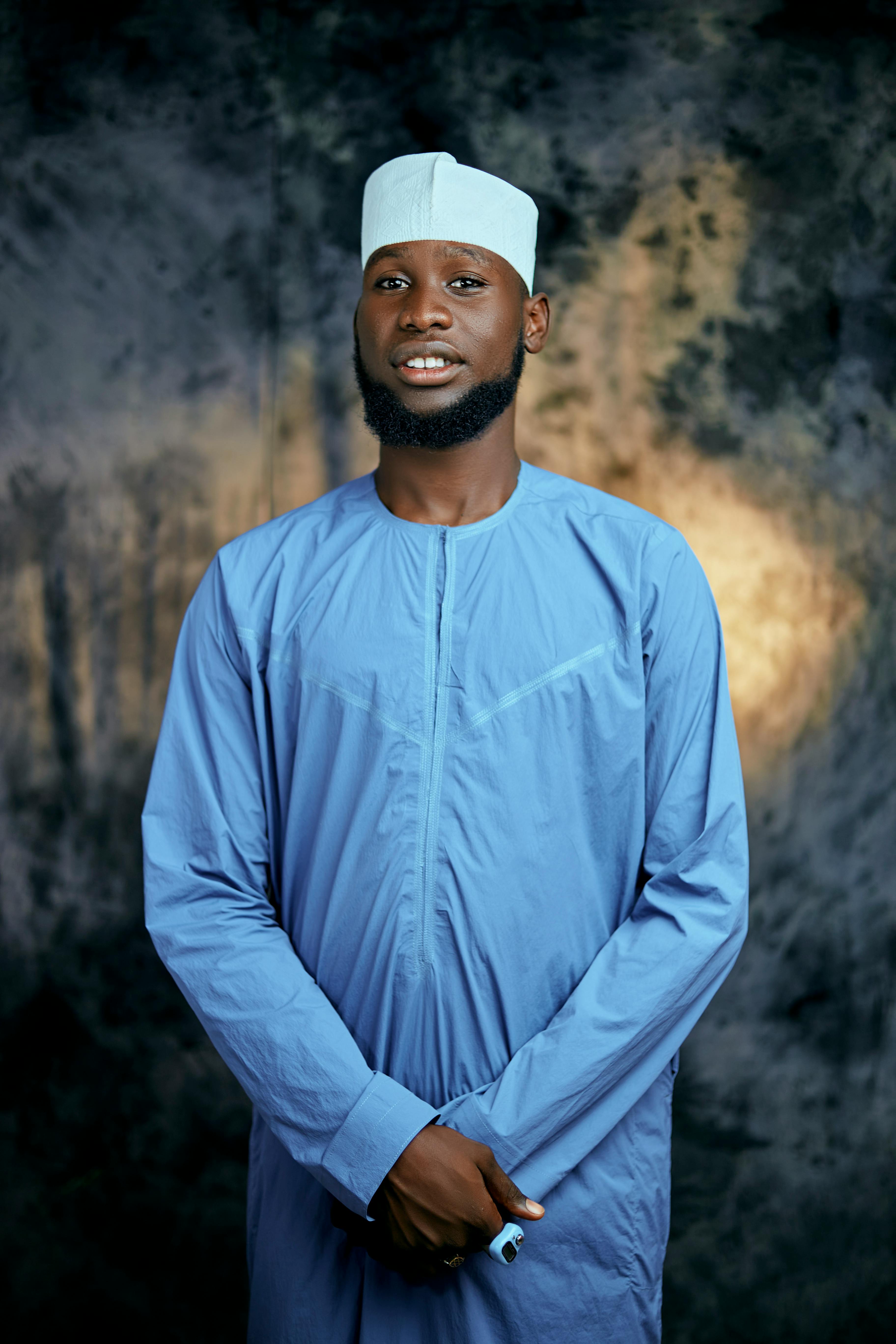 A smiling man in traditional outfit against a studio backdrop, conveying cultural elegance.