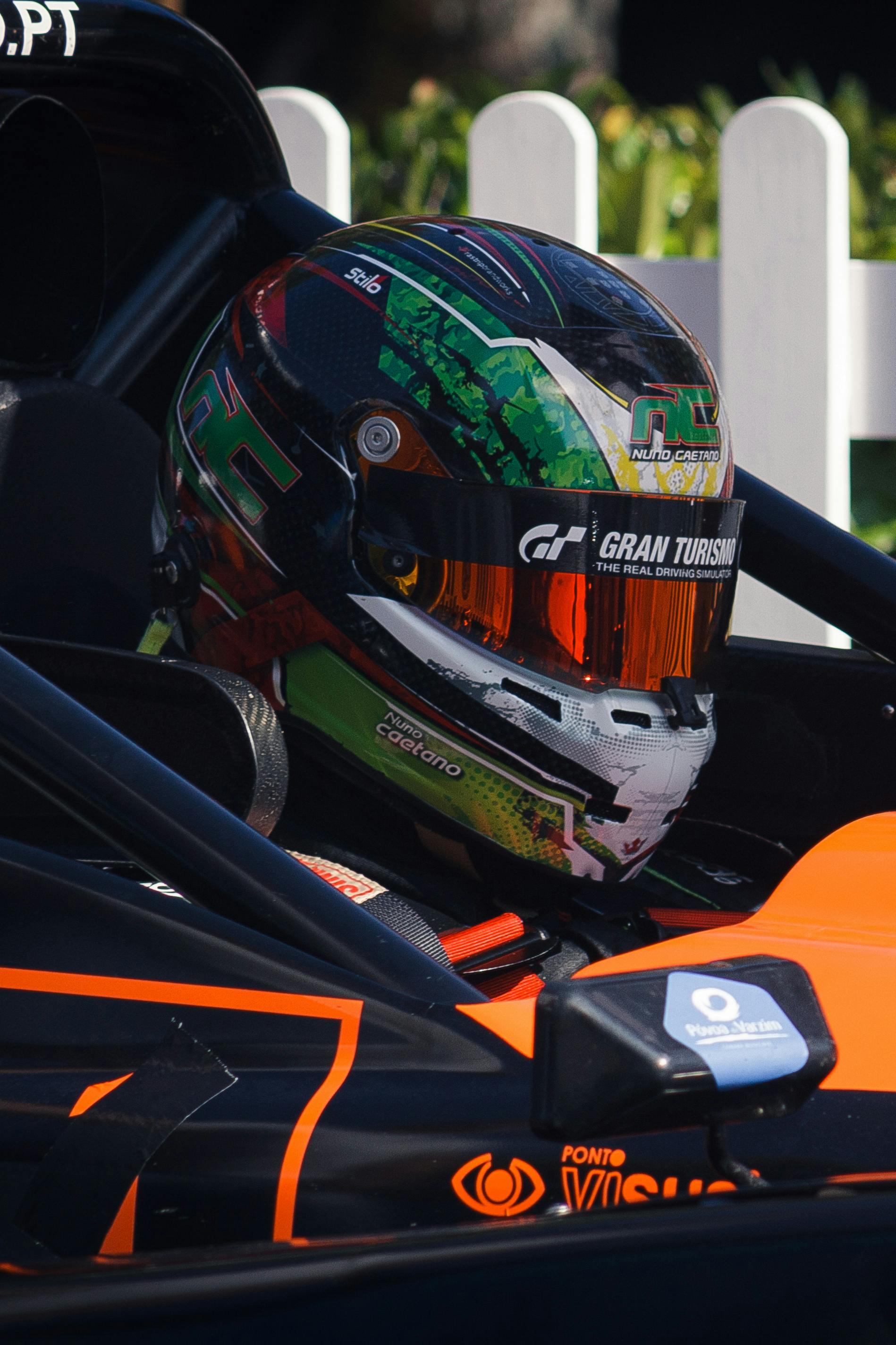 Detailed view of a race car driver in helmet, showcasing vibrant design and branding.