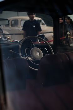 Classic car interior view through window, highlighting steering wheel.