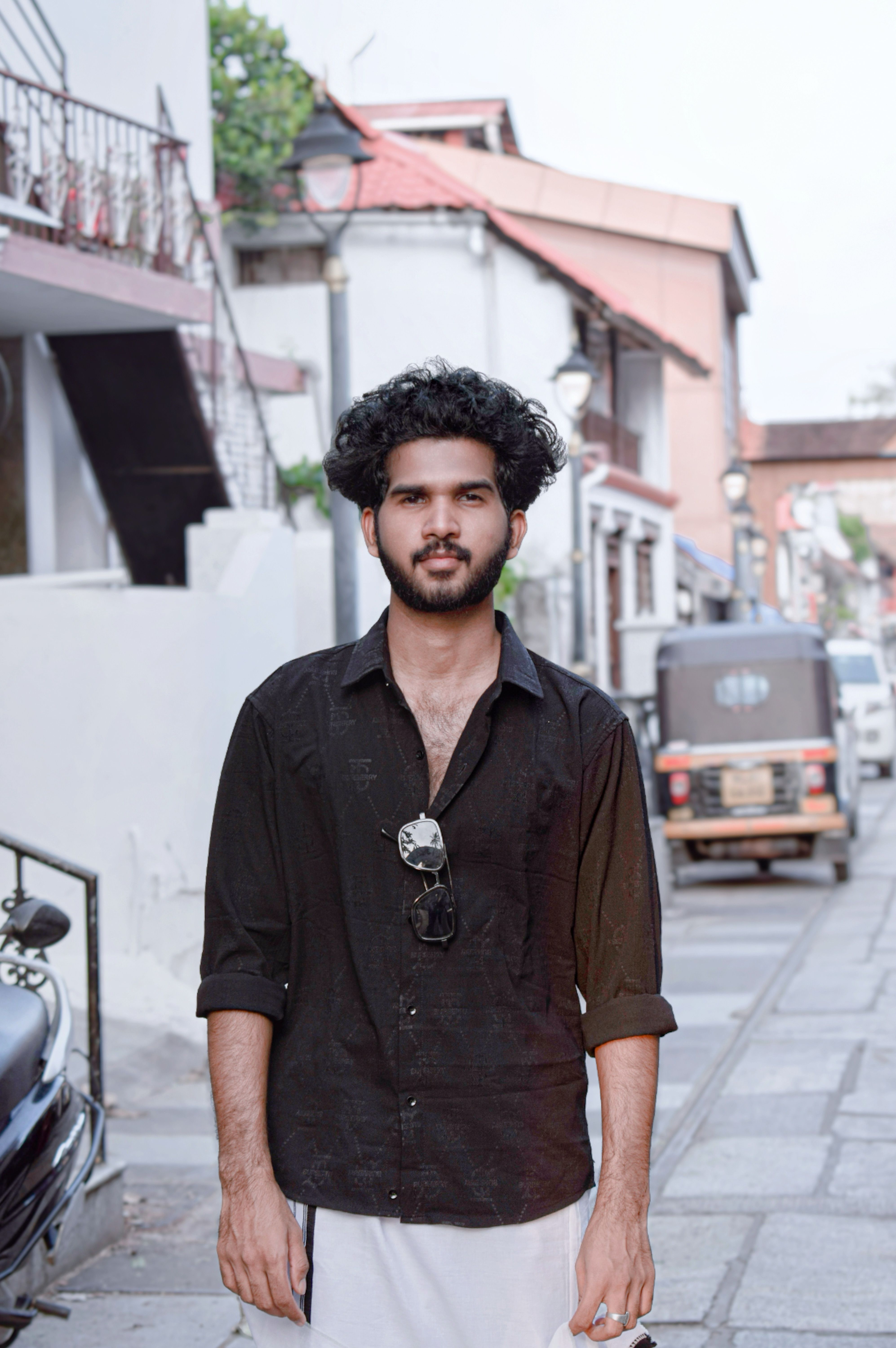 A young man stands confidently in an urban street, exuding modern style and charm.