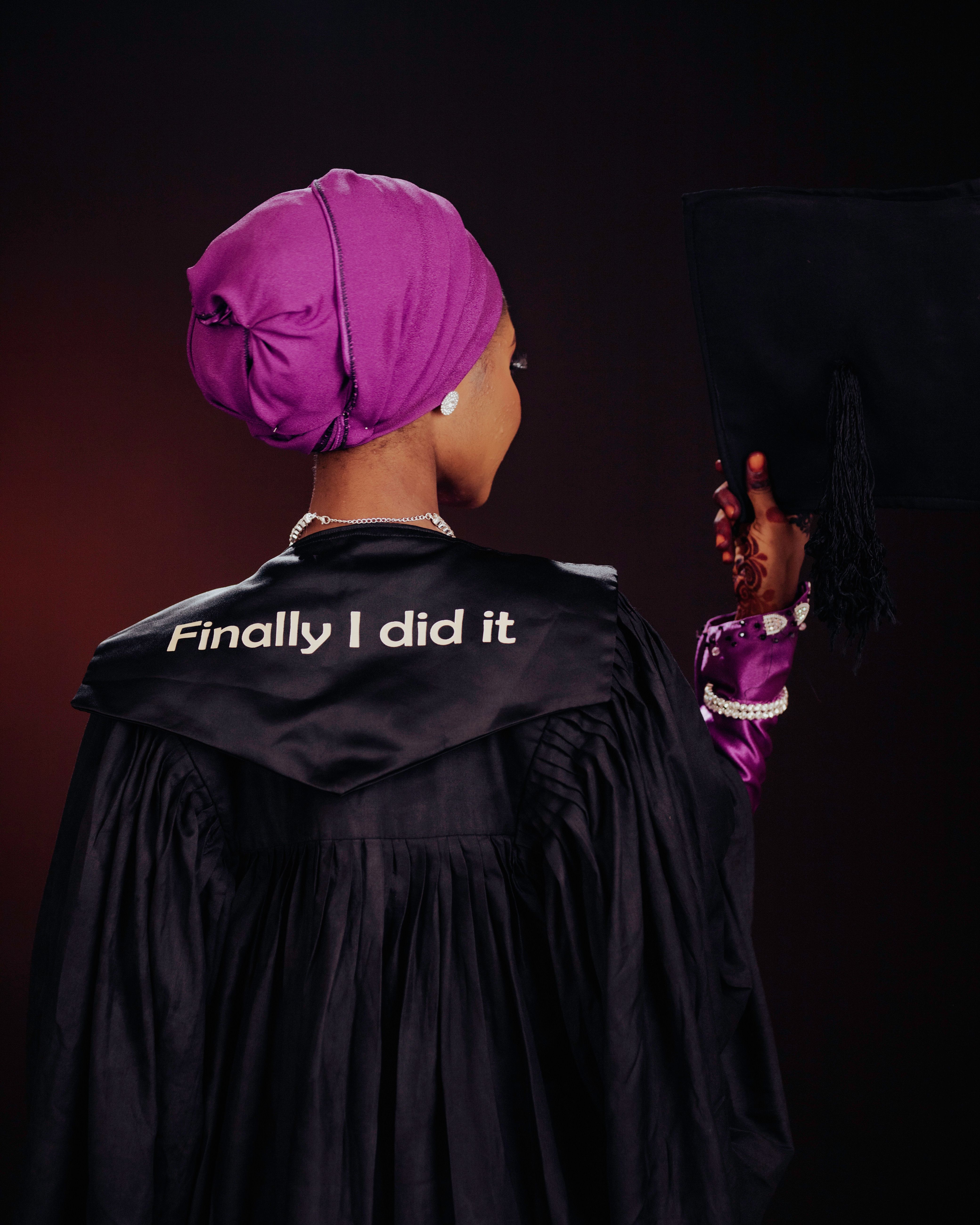 Rear view of a female graduate in cap and gown celebrating her achievement.