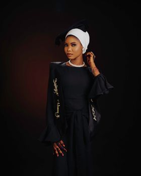 Portrait of a young female college graduate in cap and gown, celebrating achievement.