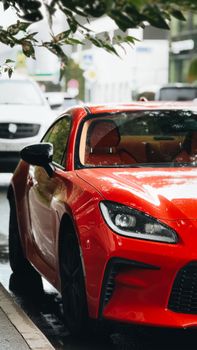 A sleek red sports car parked on a wet city street, capturing urban elegance.