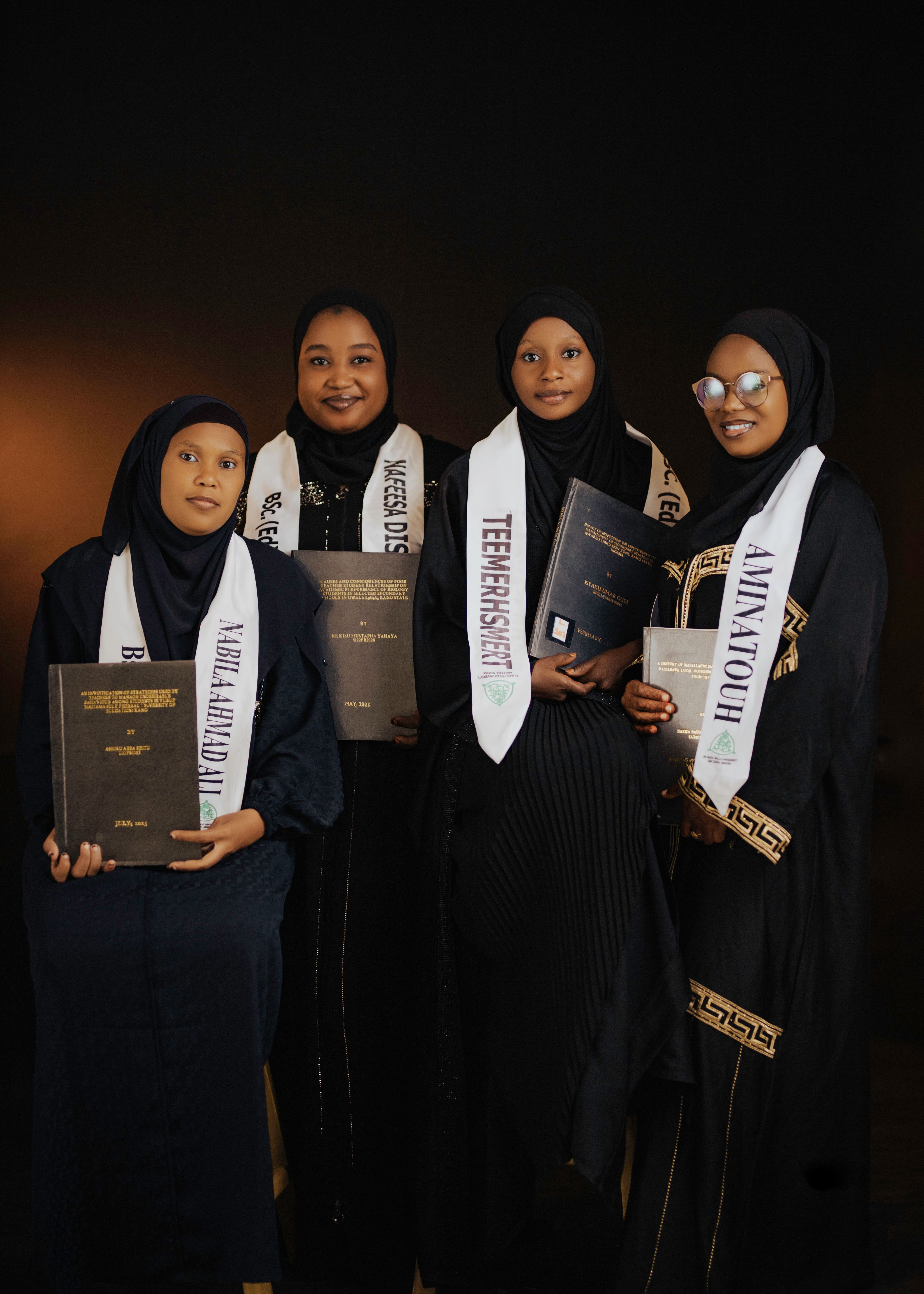 Four diverse female graduates proudly holding diplomas after a university graduation ceremony.