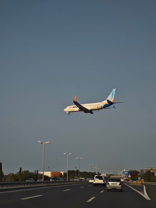 Free An airplane approaching landing over a busy highway under a clear sky. Stock Photo