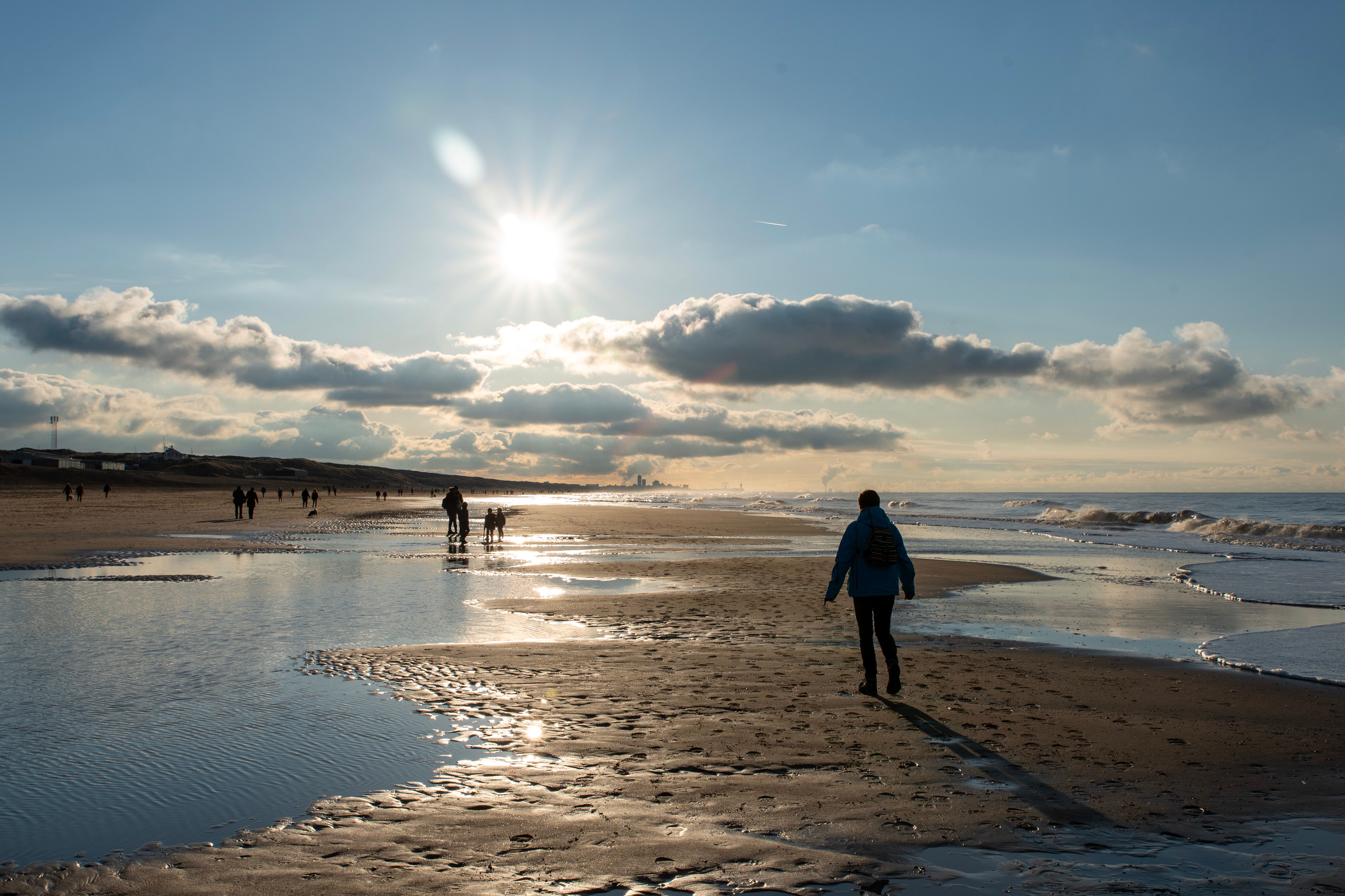 Serene Beach Sunset with People Walking Silhouettes · Free Stock Photo