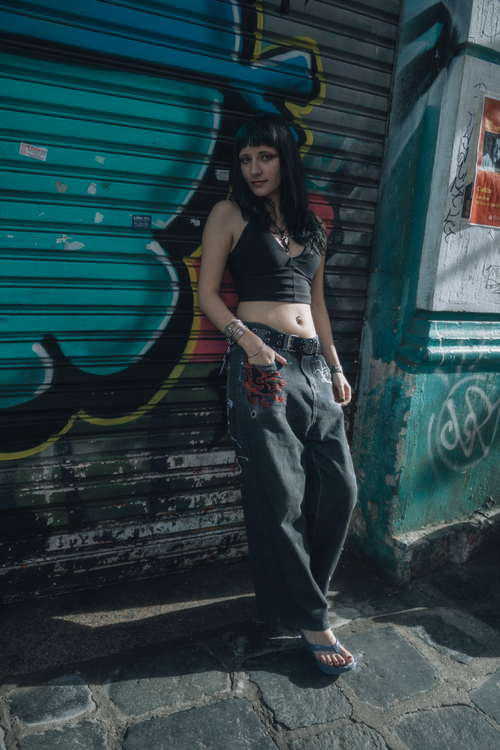 Free Stylish young woman posing against a graffiti wall in an urban setting, wearing casual streetwear. Stock Photo
