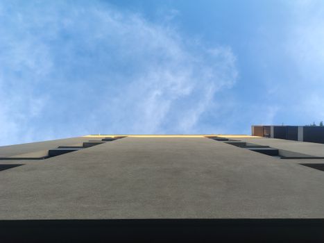 Upward perspective of a modern building under a clear blue sky, emphasizing architecture.