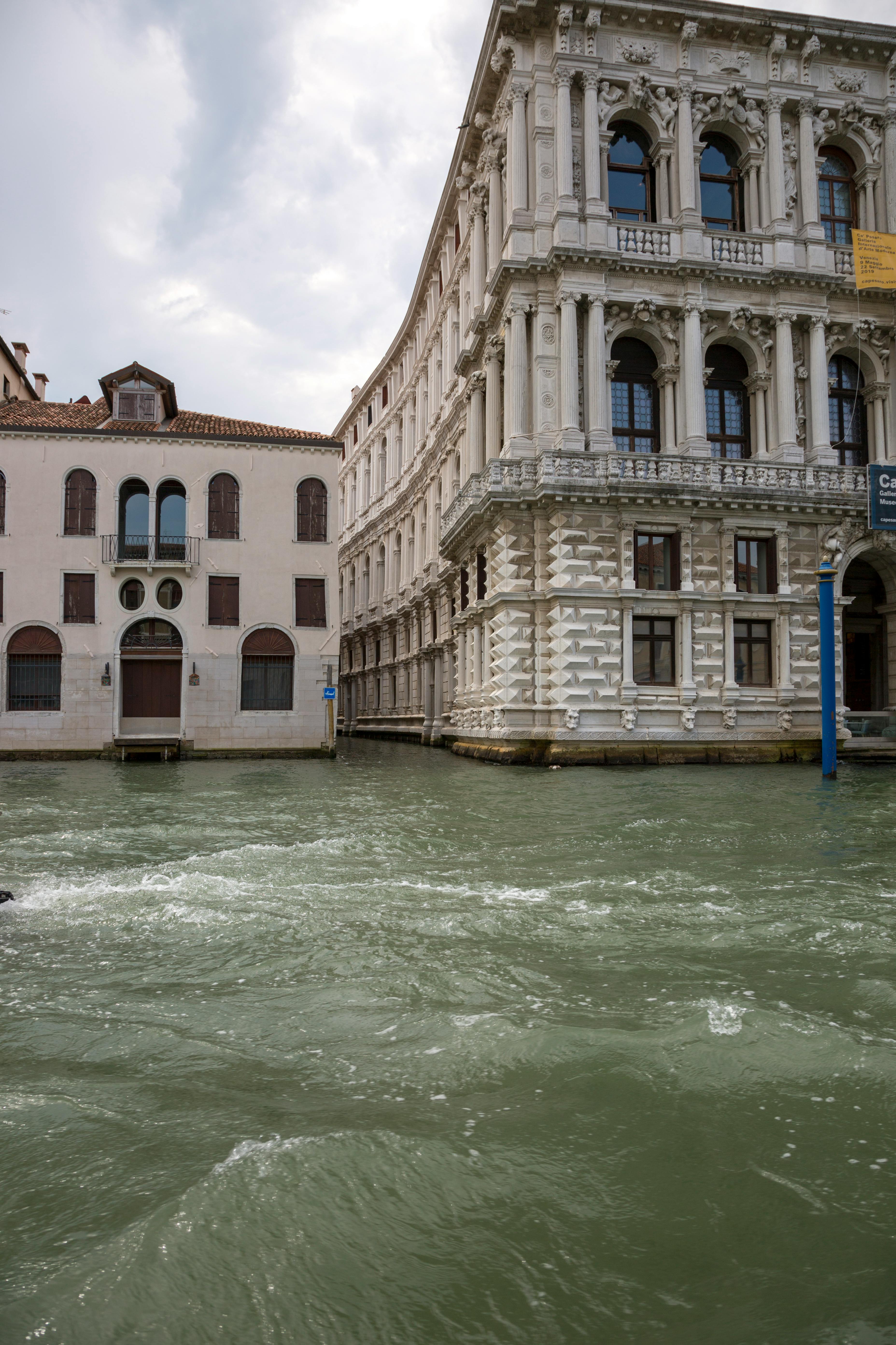 Intricate historic buildings beside a Venetian canal, showcasing classic architecture amidst flowing water.