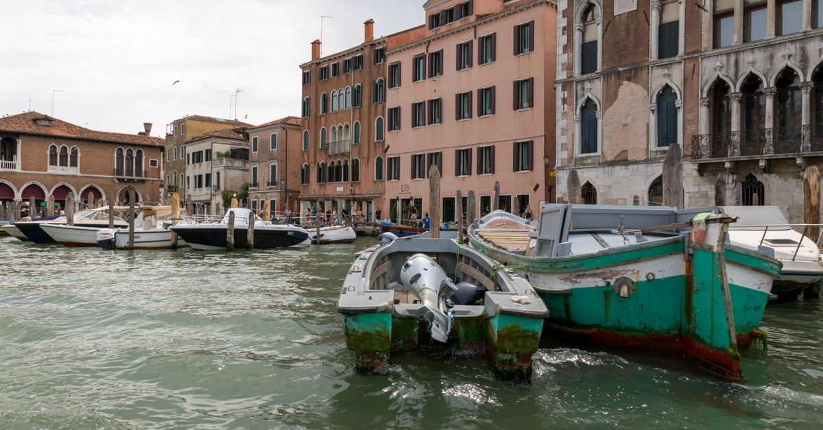 A view of boats on a picturesque Venetian canal alongside historic buildings.