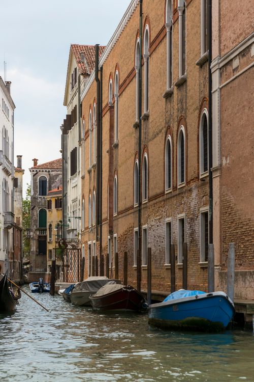 Free Peaceful view of a Venice canal with boats and historic buildings along the waterway. Stock Photo