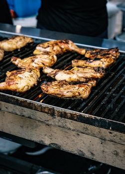 Juicy grilled chicken pieces sizzling on an outdoor barbecue grill.