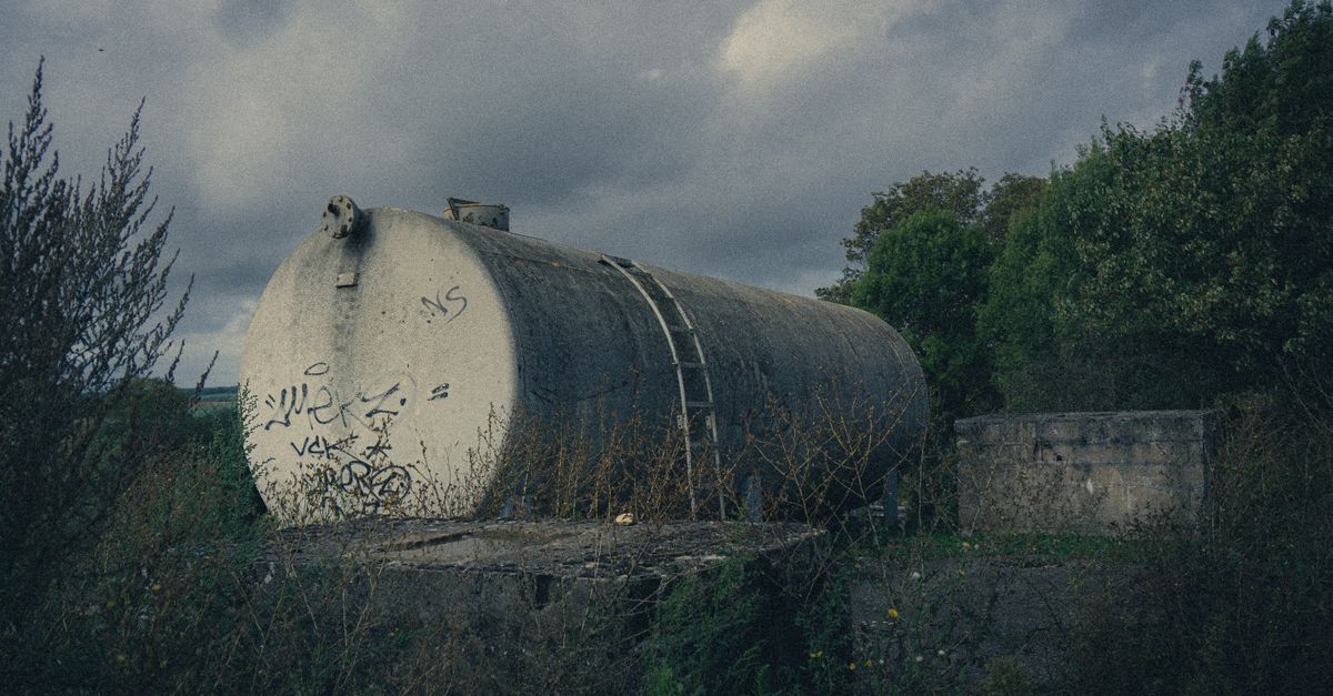 A vintage cistern with graffiti in a natural, overgrown setting in La Ferté-Milon, France.