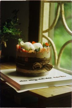 Delicious layered birthday cake with strawberries by a sunlit window.