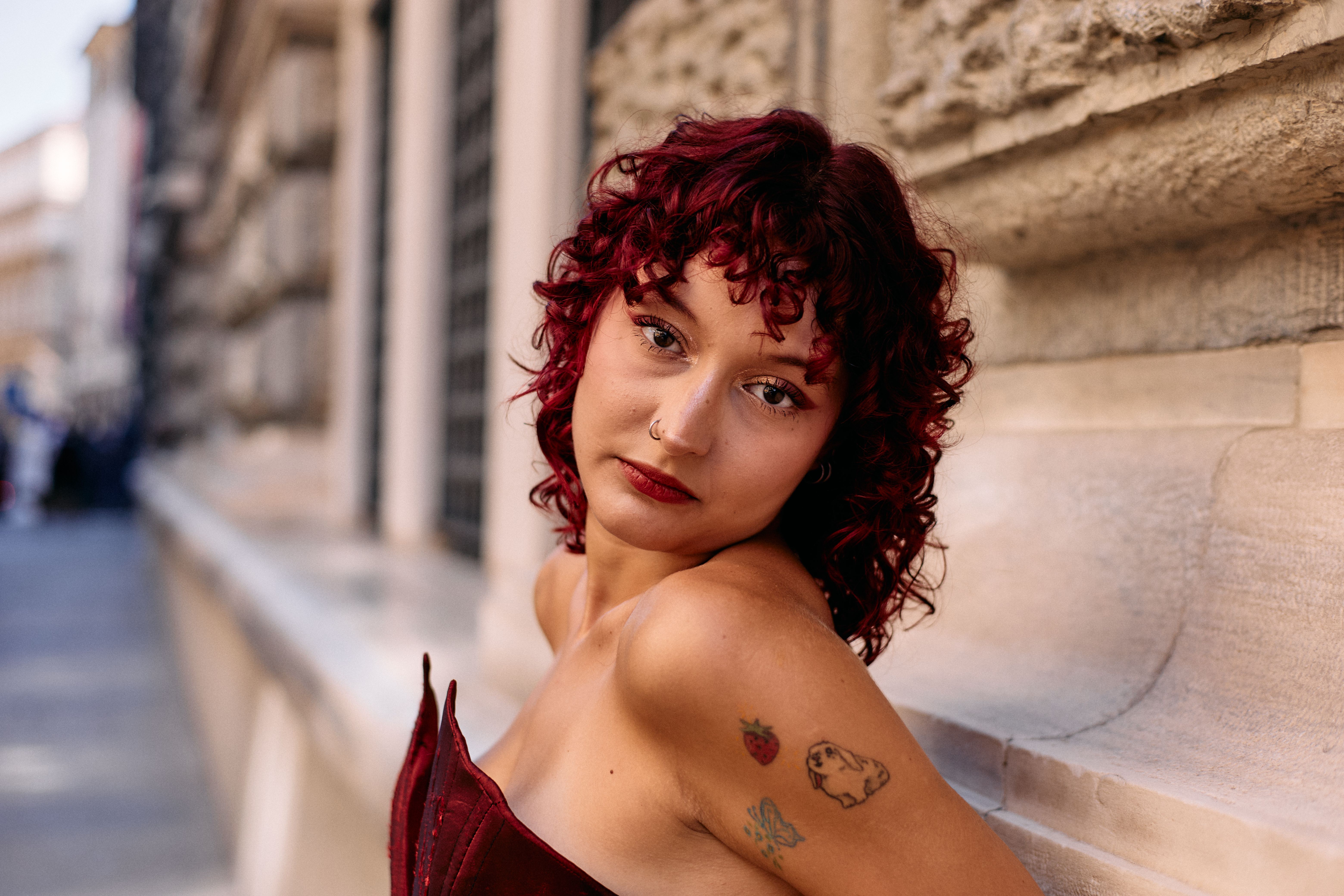 Une femme à la mode avec des tatouages s'appuie contre un mur texturé à Istanbul, mettant en valeur son style urbain.