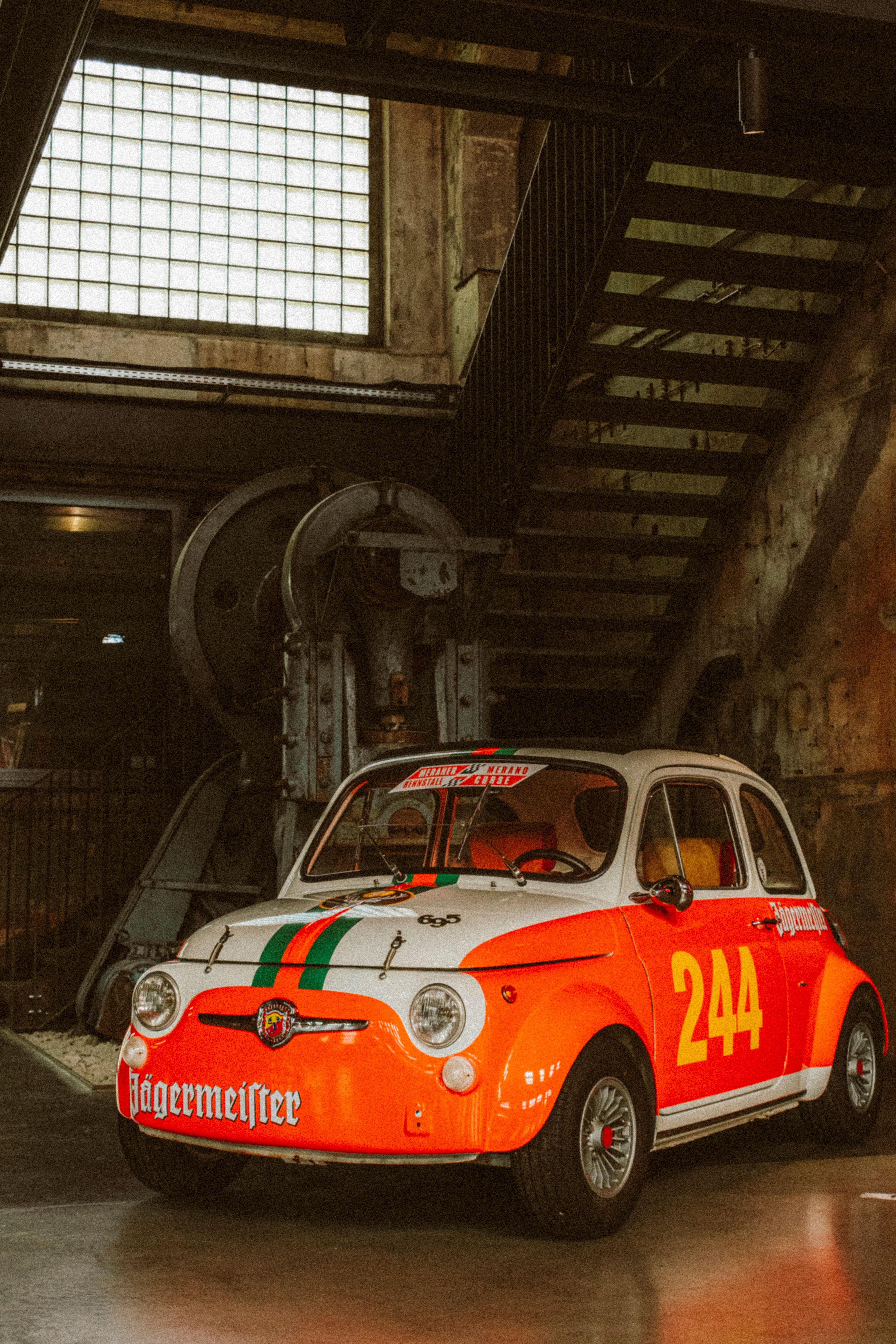 免費 一輛帶有 Jägermeister 品牌標誌的經典菲亞特 500 汽車，在室內工業環境中拍攝。 圖庫相片