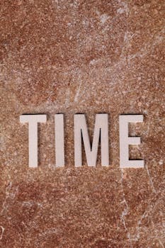 Closeup of the word "TIME" on a brown textured background, symbolizing time concepts.