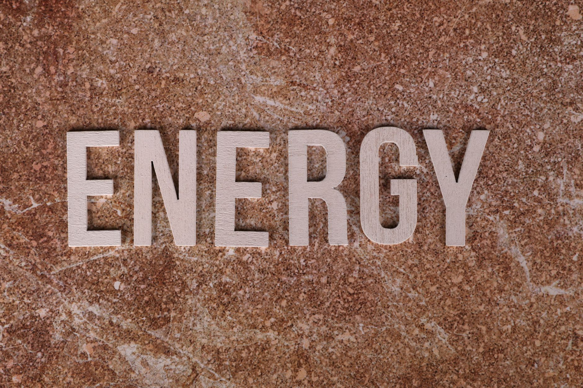 Word 'Energy' on natural stone texture, symbolizing raw power.
