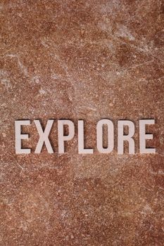 The word 'Explore' on a textured brown surface, conveying adventure and curiosity.