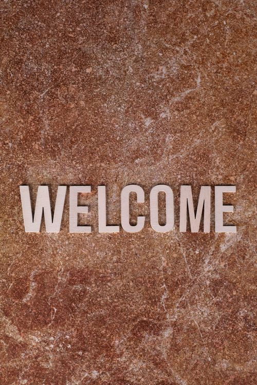 Free Close-up of a 'Welcome' sign on a textured brown stone surface, perfect for hospitality themes. Stock Photo
