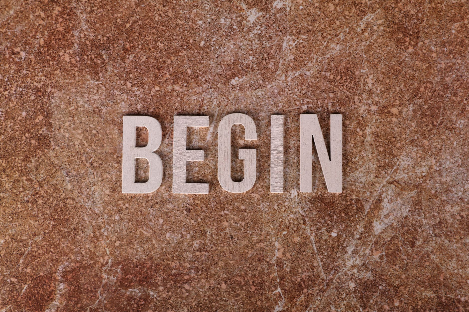 Text 'BEGIN' on a textured stone background, symbolizing a fresh start.