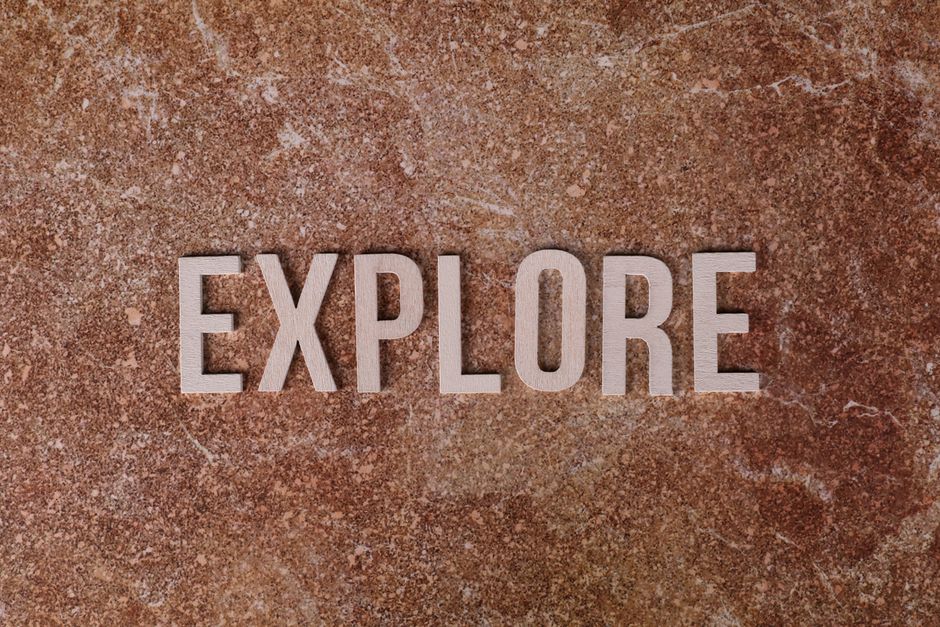 The word 'Explore' on a textured brown stone surface.