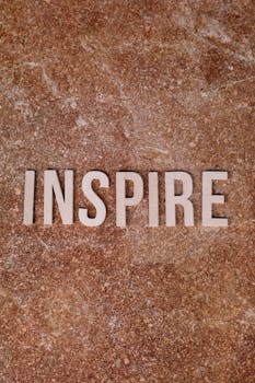The word 'Inspire' displayed on a textured brown stone surface, creating a motivational vibe.