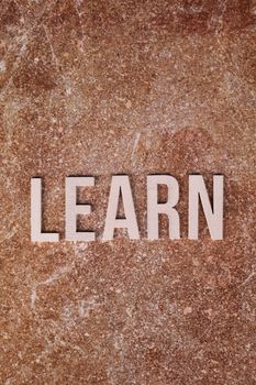 Inspirational word 'LEARN' displayed on a textured marble background.