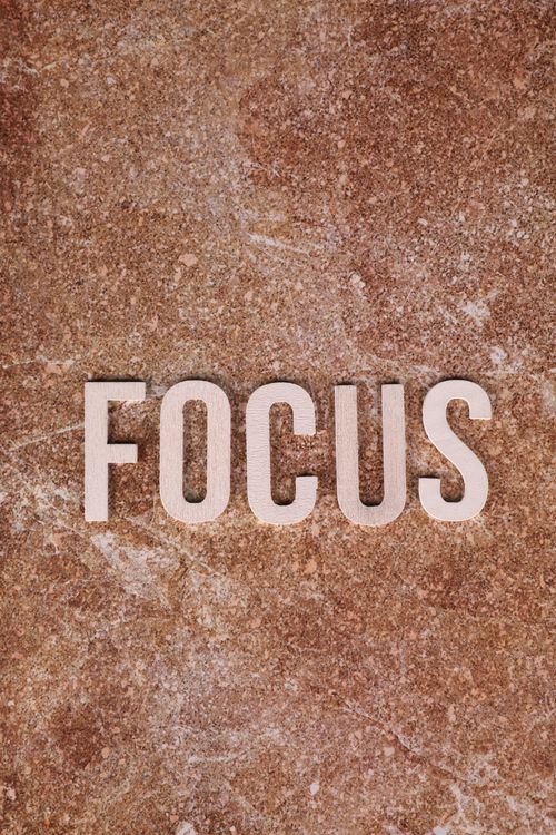 Free Top view of 'FOCUS' arranged with wooden letters on a textured stone surface. Stock Photo