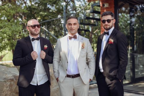 Free Three groomsmen in formal suits pose outdoors, exuding style and elegance. Stock Photo