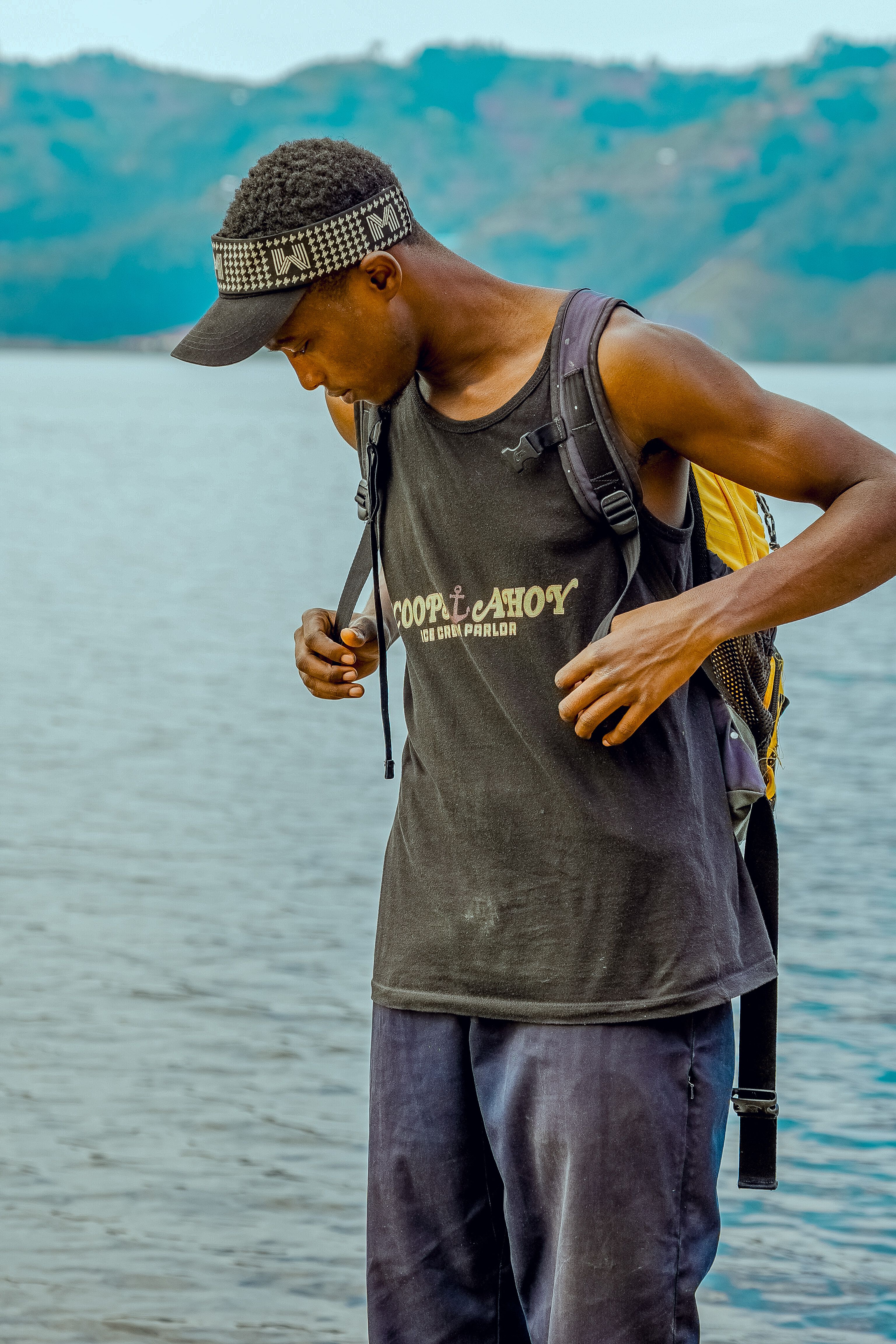 A young man with a backpack stands by a serene lake, ready for adventure.