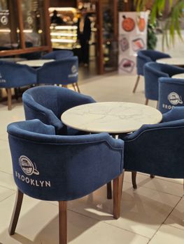 Stylish cafe setting with a marble table surrounded by blue chairs labeled Brooklyn.