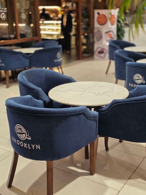 Free Stylish cafe setting with a marble table surrounded by blue chairs labeled Brooklyn. Stock Photo