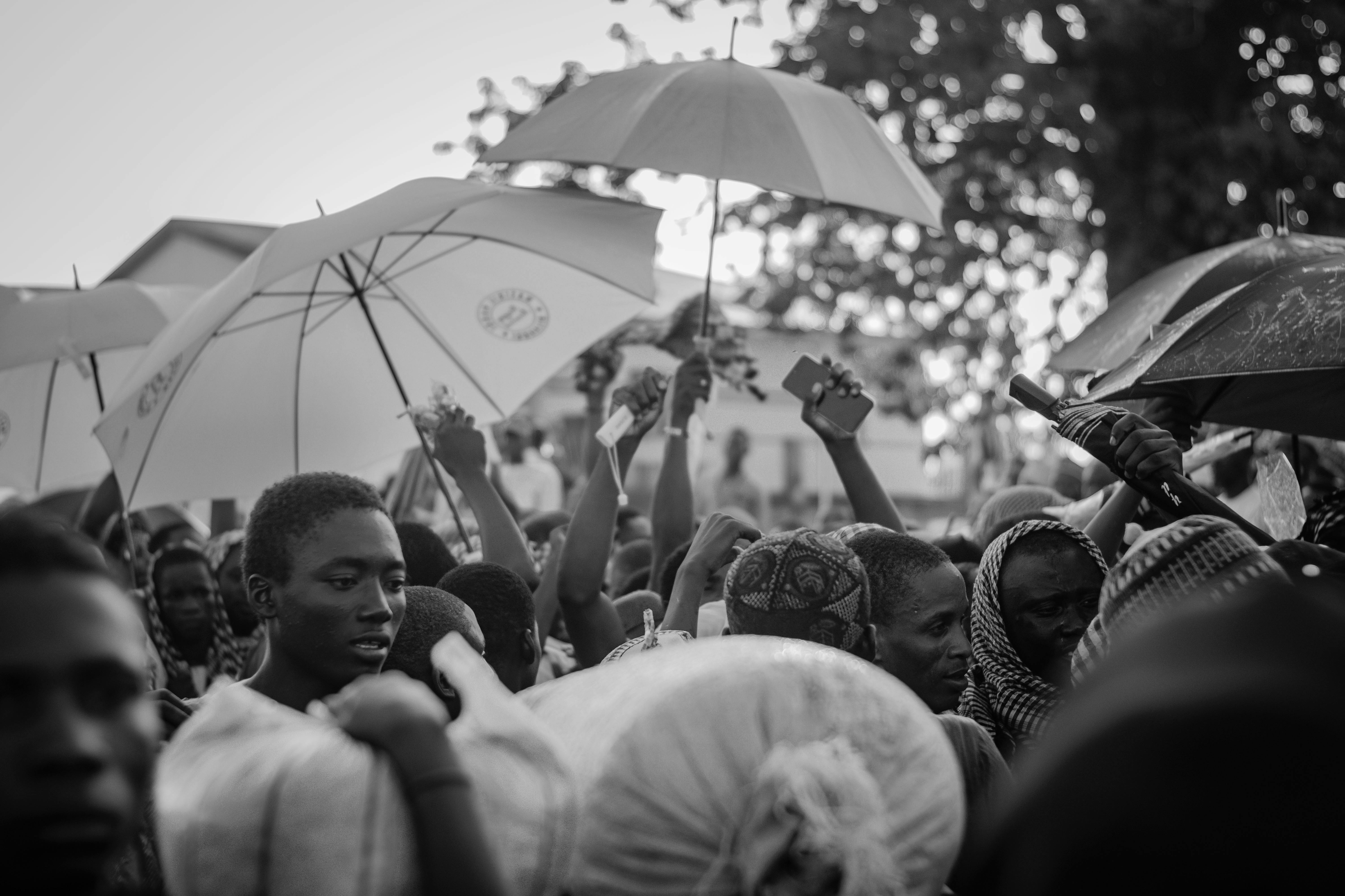 Black and white photo of people under umbrellas in Zaria City, Nigeria.