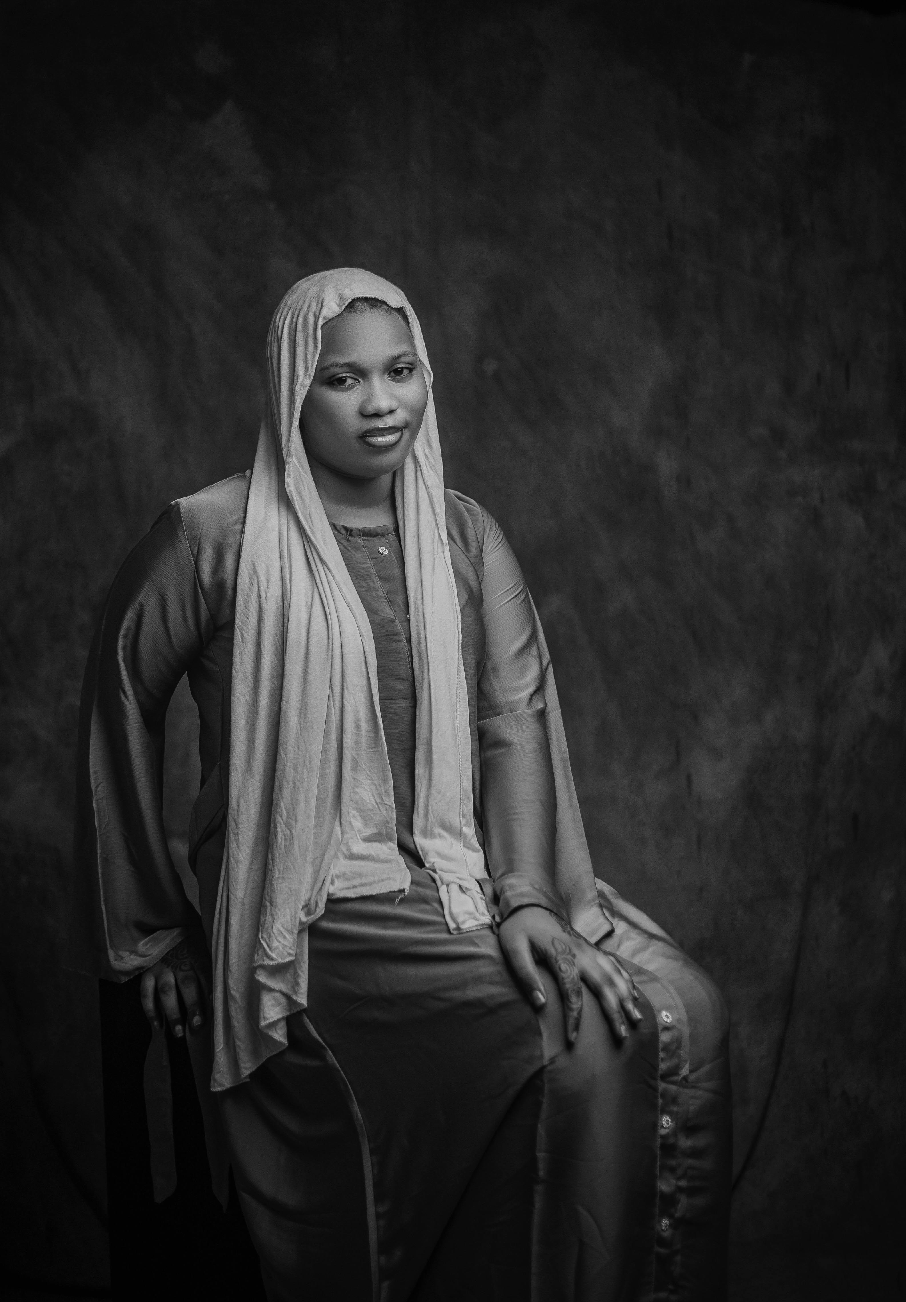 Kostenlos Ein zeitloses Schwarzweißporträt einer Frau mit Hijab, die mit heiterem Gesichtsausdruck dasitzt. Stock-Foto