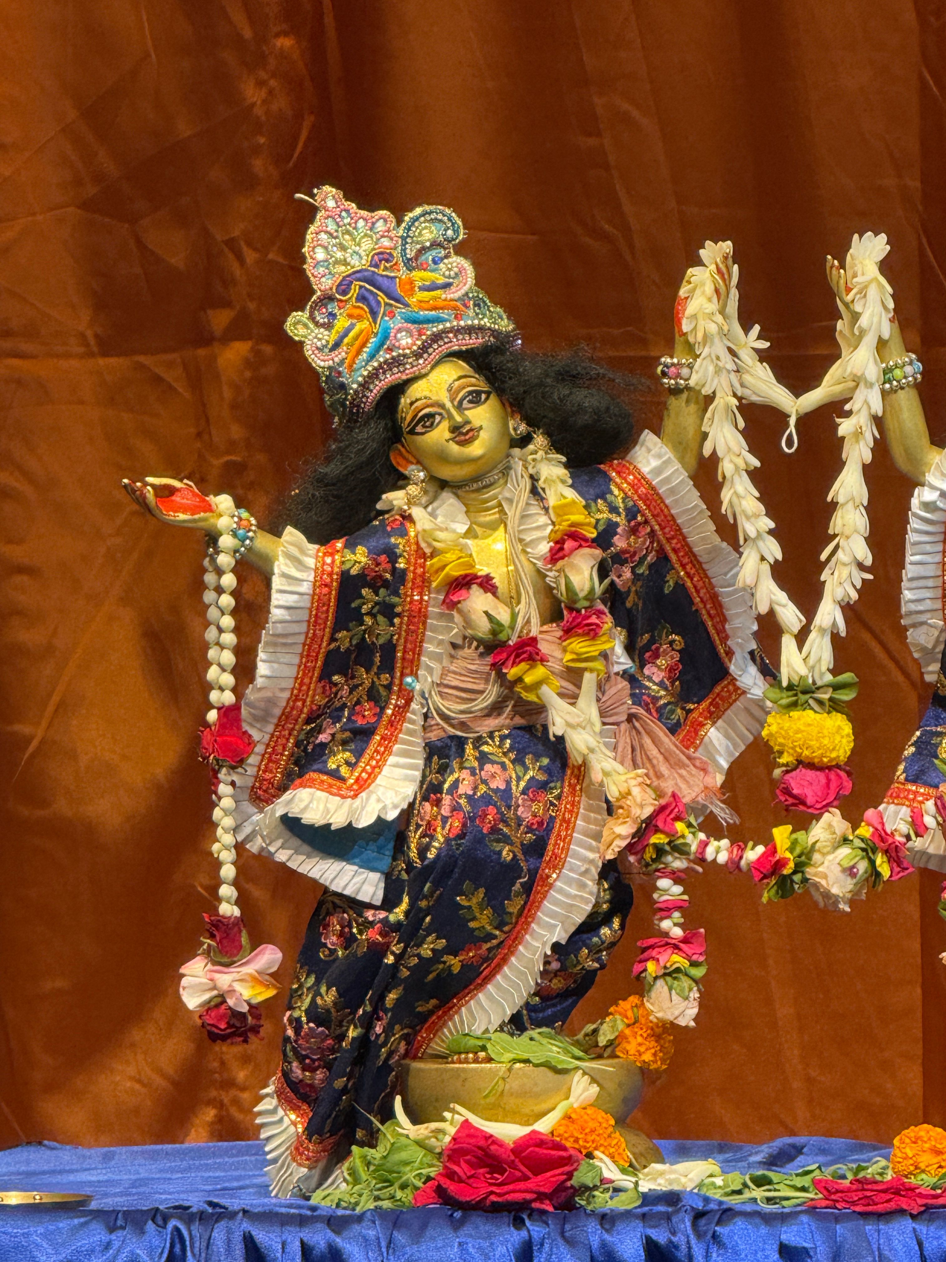 Colorful statue of a Hindu deity adorned with intricate clothing and floral garlands.