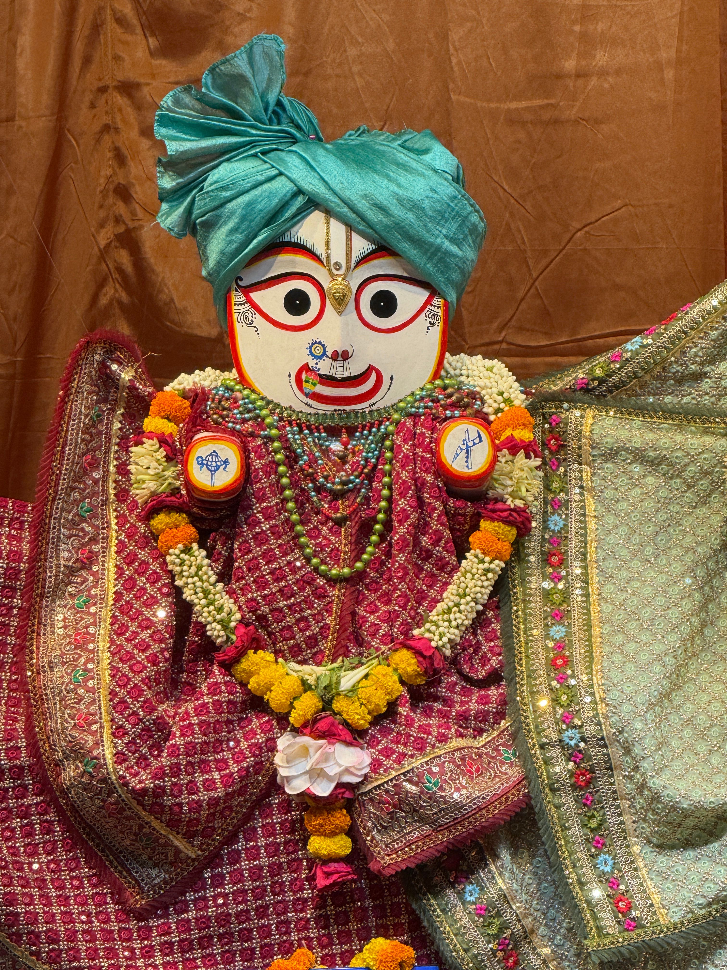Vibrant display of a traditional Indian deity adorned with intricate fabrics and ornaments.