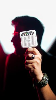 Silhouette of a person holding a small RGB LED light, creatively illuminated in a studio setting.