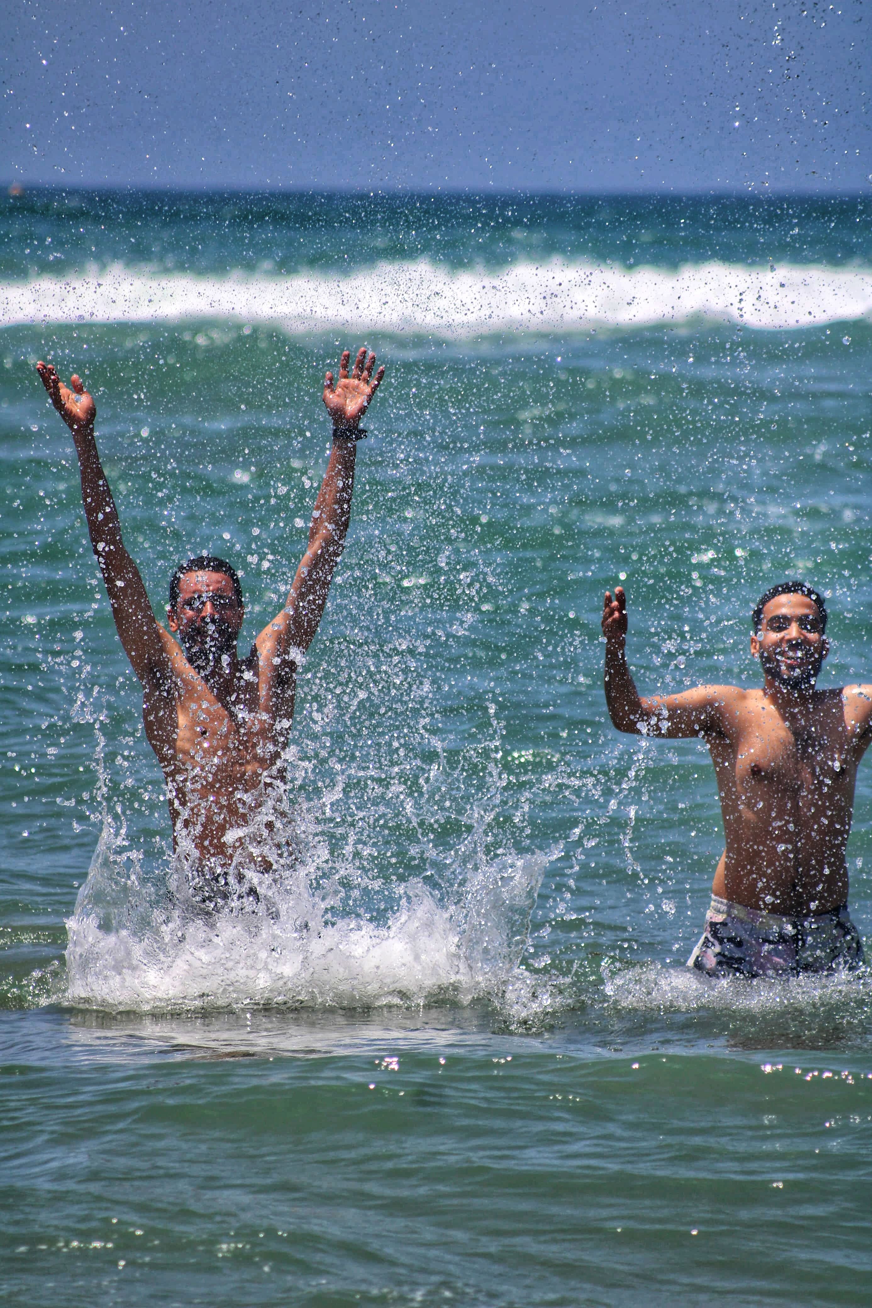Joyful Beach Day: Two People Splashing in Ocean Waves · Free Stock Photo