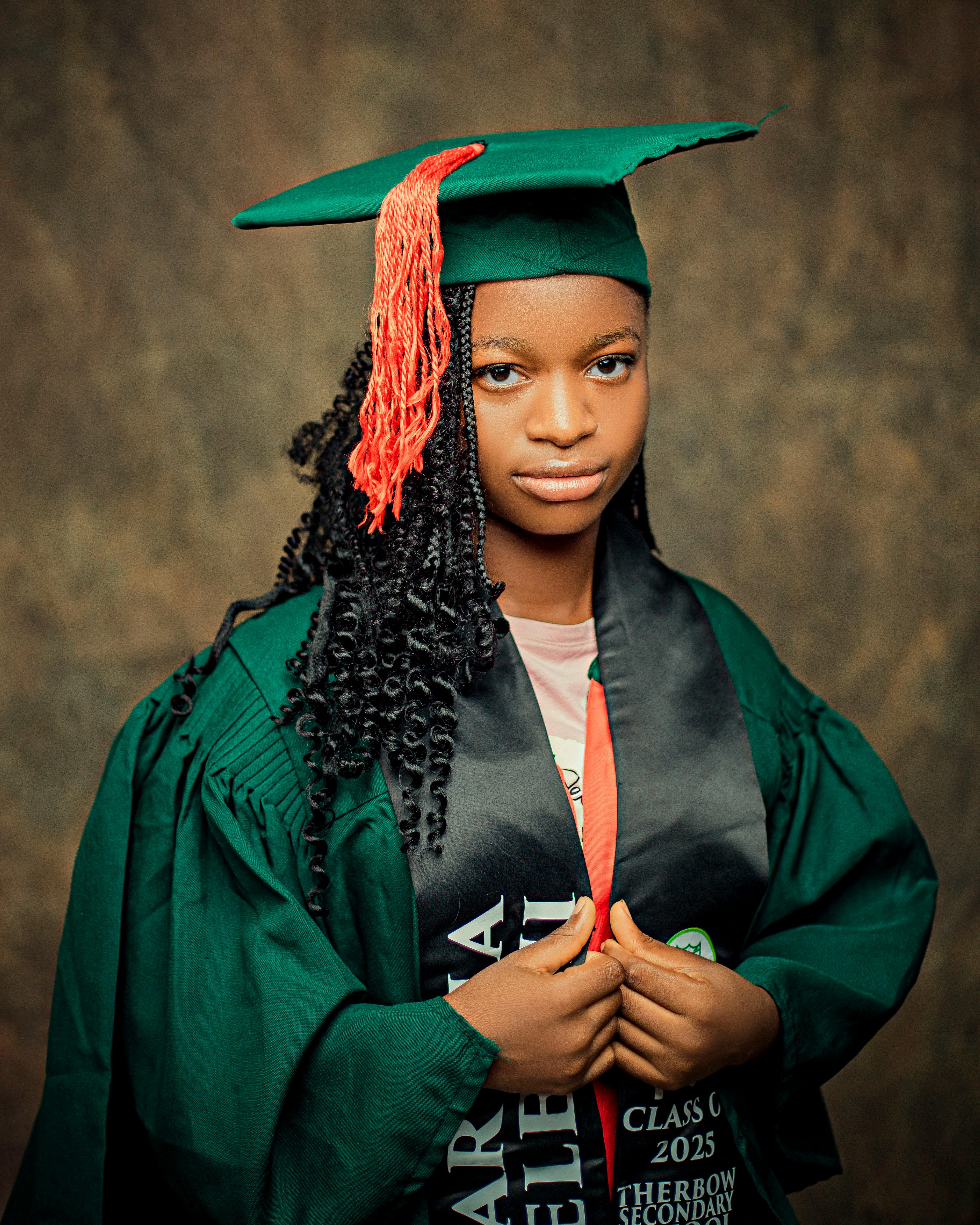A young woman in graduation attire with a green gown and cap, celebrating a milestone.